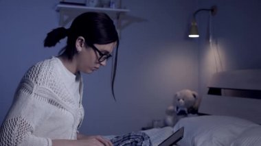 Kız geceleri dizüstü bilgisayarda çalışıyor. Çekici, serbest çalışan genç bir kadın ya da gözlüklü ve başında at kuyruğu olan bir öğrenci karanlık bir gecede odada dizüstü bilgisayarda yazı yazıyor. Orta boy.