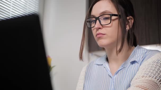 A rapariga assoa-lhe o nariz. Mulher atraente trabalhando no laptop, digitando quebras e sopra o nariz no lenço, coloca lenço de papel sujo na mesa. Freelancer menina doente no trabalho, conceito gripe resfriados — Vídeo de Stock