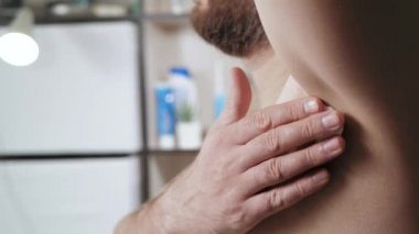 Koltuk altı traşı konsepti. Sakallı beyaz adam banyoda, sol koltuk altını tıraş etmek için köpük sürüyor. Yan görüş. Yakın plan.