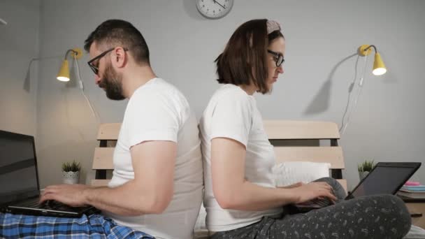 Famille freelance travaillant à domicile concept. Homme et femme assis dos à dos sur le lit dans la chambre à coucher et en même temps travailler la dactylographie sur le clavier de l'ordinateur portable. Gros plan — Video