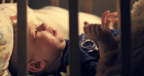Mutter zieht weinendes Baby nachts aus dem Kinderbett, warmes Licht von der Lampe erhellt Bett und Kind. Nahaufnahme — Stockvideo