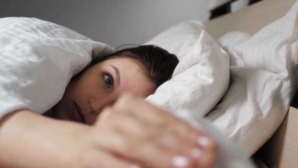 Женщина с насморком лежит в постели, достает бумажную салфетку и высморкается. Холод, грипп, аллергия, пыль, кошачьи волосы, ринит, гипотермия, концепция сухого воздуха. Крупный план — стоковое видео