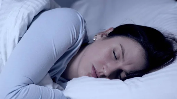 Девочка спит и хмурится. Кошмары и кошмары. Молодая привлекательная кавказская девушка спит одна в постели и испытывает негативные эмоции от снов. Крупный план — стоковое фото