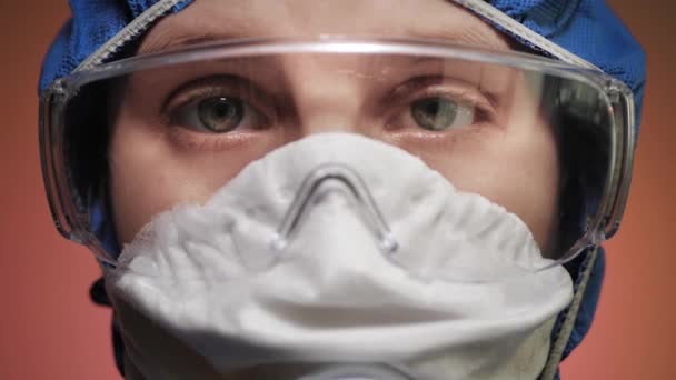 Πορτρέτο κορίτσι σε μάσκα αναπνοής με προστατευτική στολή και γυαλιά κοιτάζοντας την κάμερα. Προειδοποίηση, επιδημία, πανδημία, COVID-19, έλεγχος ασθενειών, κίνδυνος μόλυνσης. Κλείσε. — Αρχείο Βίντεο