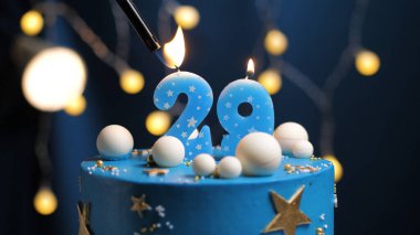 Birthday cake number 29 stars sky and moon concept, blue candle is fire by lighter. Copyspace on right side of screen. Close-up view clipart