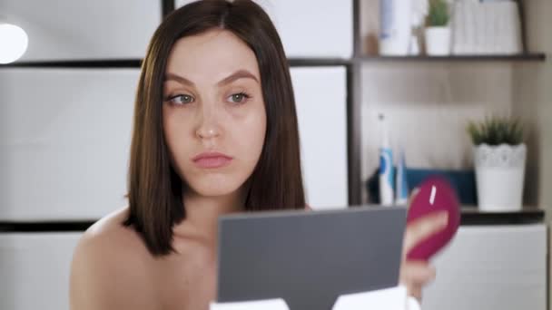 Holka se učesala. Atraktivní mladá žena v koupelně se podívá do zrcadla a učesá si oschlé vlasy hřebenem. Make-up doma, péče o vlasy, účes vlastní koncepce. Detailní záběr — Stock video