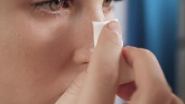 Kız kapatıcı uyguluyor. Cildine kapatıcı krem süren çekici bir kadının makro çekimi. Güzellik uzmanı, evde tek başına makyaj. Yakın plan.