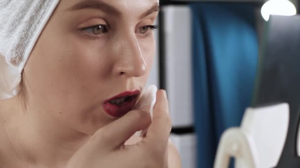 Mädchen wäscht Make-up. Attraktive Frau im Badezimmer schaut in den Spiegel und wischt Lippenstift mit Wattepad ab. Kosmetikerin, Make-up allein zu Hause. Nahaufnahme — Stockvideo