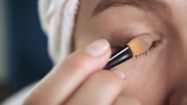 Een meisje met een oogschaduw. Macro shot van gezicht aantrekkelijke vrouw schilderen schaduw op de huid rond haar ogen. Make-up kunstenaar, schoonheid, lichaamsverzorging, gezichtsreiniging, make-up, datum of feest concept — Stockvideo