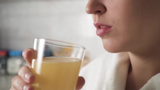 Dziewczyna pije sok pomarańczowy. Kobiety przynoszą szklankę soku pomarańczowego na twarz i piją. Zbliżenie — Wideo stockowe