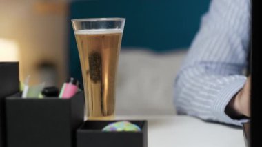 El masadan bir bardak bira alır.