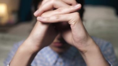 Kız dua etmek için iki elini birleştiriyor, yatak odasının yanında yere oturuyor. Yaklaşın ve yavaş çekim görünümü