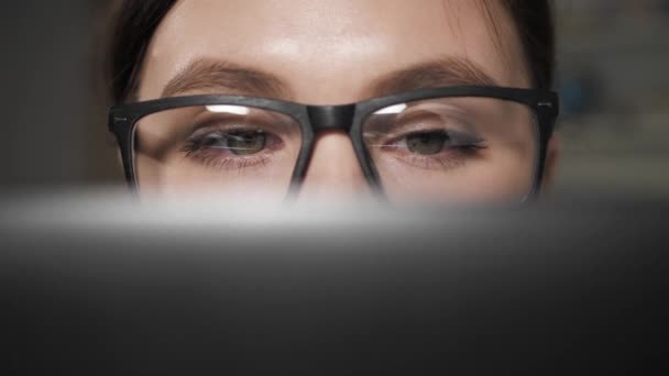 La mujer trabaja en el portátil. Primer plano de los ojos femeninos en gafas mirando la pantalla del ordenador durante el trabajo. De cerca. — Vídeos de Stock