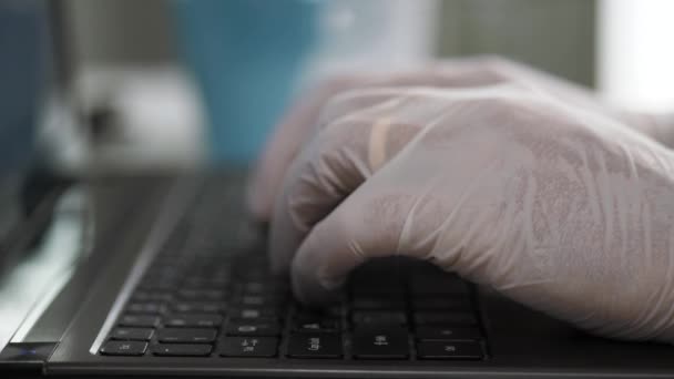 Las manos en guantes de látex blanco están escribiendo en el teclado del ordenador portátil. Pandemia, epidemia, concepto de protección. De cerca. — Vídeos de Stock