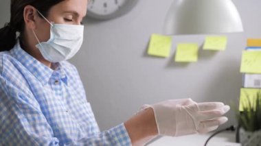 Kız koruyucu eldiven takıyor. Ofisteki genç bayan ofis çalışanı beyaz lateks eldivenlerini giyer ve dizüstü bilgisayarında klavyede yazmaya başlar. Yakın çekim ve yavaş çekim