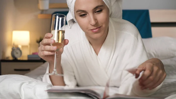 Chica Bebiendo Champán Leyendo Revista Mujer Atractiva Dormitorio Albornoz Blanco —  Fotos de Stock