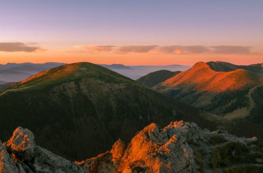 mountain peaks and clouds illuminate the rising sun