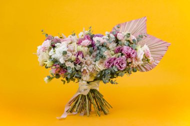 Güzel bir buket gül ve sarı arka planda kurutulmuş palmiye yaprakları.