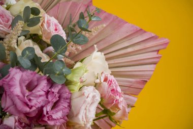 Güzel bir gül kompozisyonu ve sarı arka planda kurumuş palmiye yaprakları.