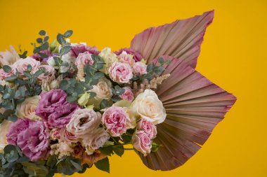 Güzel bir gül kompozisyonu ve sarı arka planda kurumuş palmiye yaprakları.