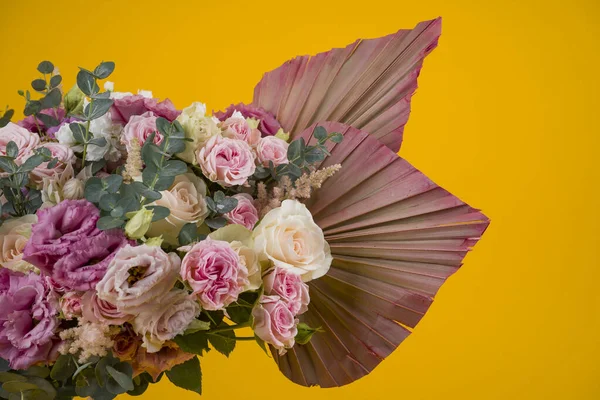 Güzel bir gül kompozisyonu ve sarı arka planda kurumuş palmiye yaprakları.