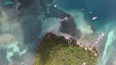 Güneşli öğleden sonra güneşli bir adanın tepesinden çekilen hava aracı Martinique Tuvaleti 'nin gölgesinde, resif bulutlarıyla çevrili.