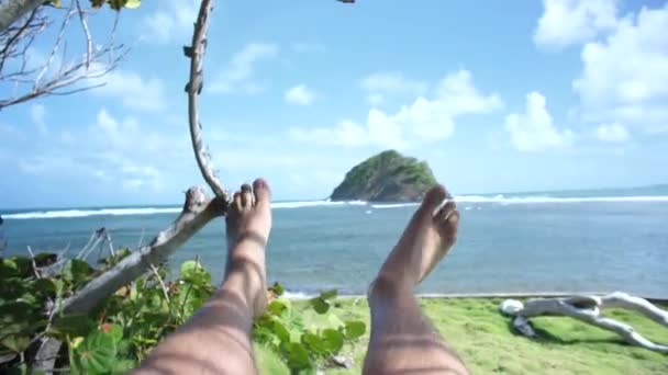 マルティニークの晴れた日に海の前でスイングする男の最初のビュー — ストック動画