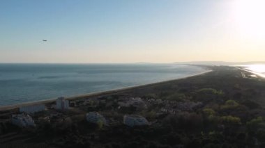 Plaj kenti la grande motte 'de kamp ve çam ağacı ticareti yapan uçak arka planda deniz kenarında Akdeniz batımına iniyor.