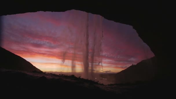 アイスランドの日没時に洞窟の中からSeljalandsfoss滝のスローモーションショット — ストック動画