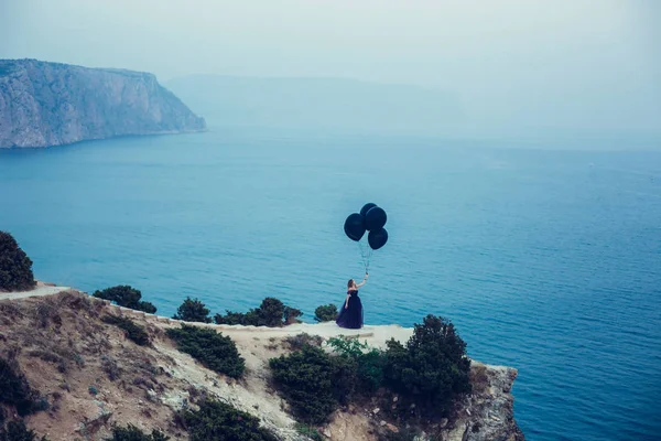 Woman in dark dress holding balloons — Stock Photo, Image