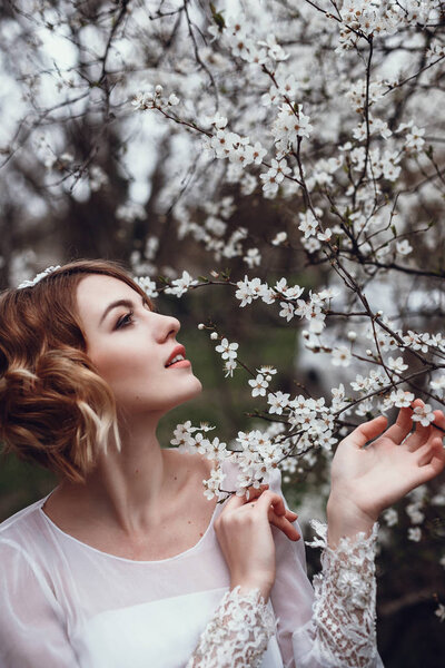 Portrait of young beautiful blonde woman in blooming garden