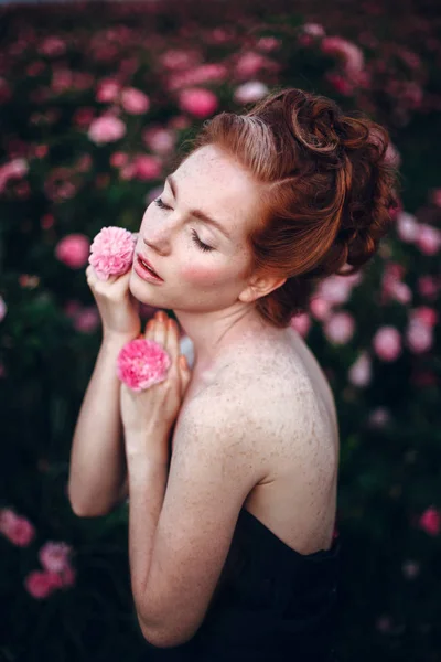 Vrouw poseren in de buurt van roze rozen — Stockfoto