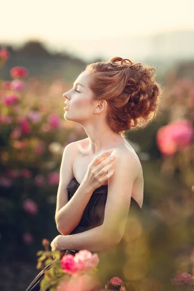 Kvinna poserar nära rosa rosor — Stockfoto