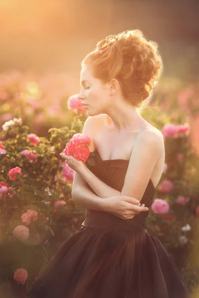 Mädchen posiert in der Nähe von rosa Rosen — Stockfoto