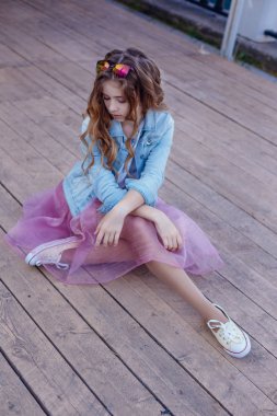 Kız açık havada oturup pembe etek