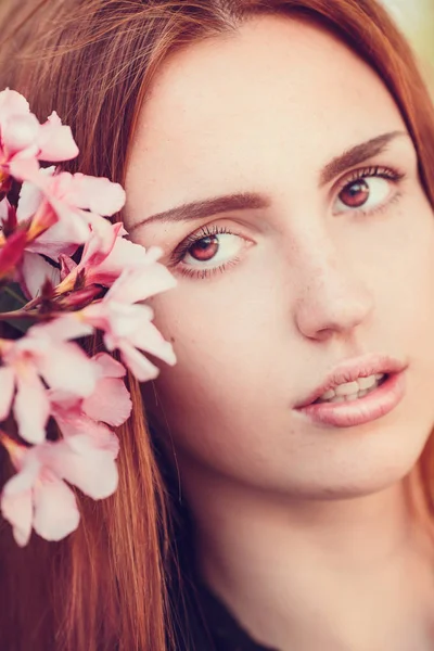 Brünettes Mädchen mit rosa Blumen — Stockfoto