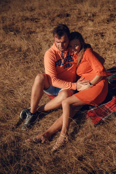 Casal esperando bebê sentado em cobertor — Fotografia de Stock