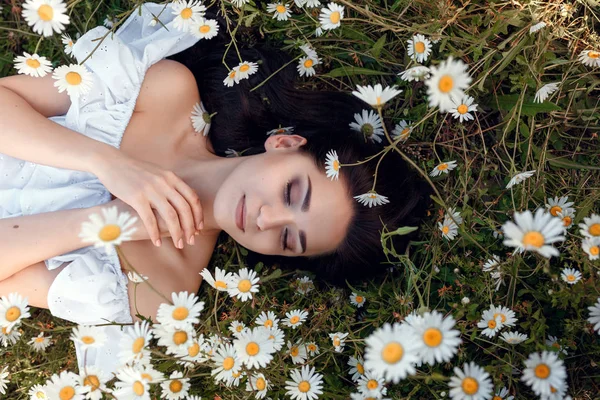 Девушка лежит на поле ромашки — стоковое фото