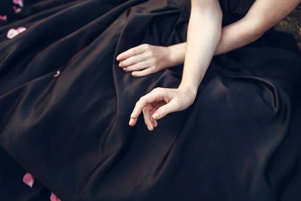 Weibliche Hände auf schwarzem Kleid — Stockfoto