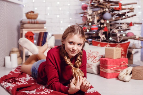 Chica sentada en el árbol de Navidad —  Fotos de Stock