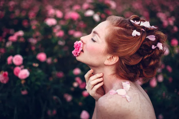 Vrouw poseren in de buurt van roze rozen — Stockfoto