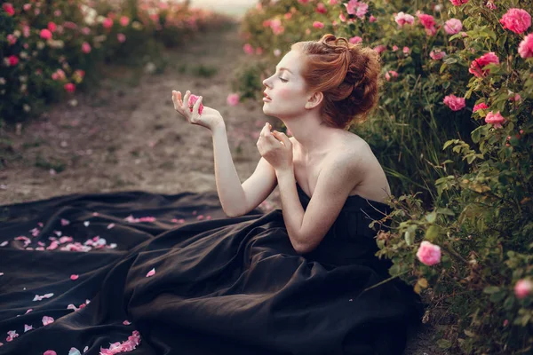 Frau sitzt neben Rosen — Stockfoto