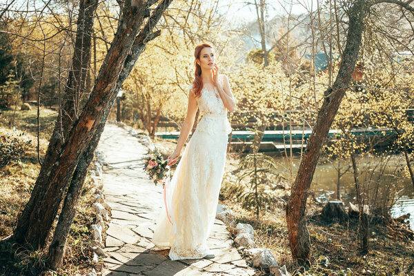 Beautiful young girl in wedding dress walking in autumn park.