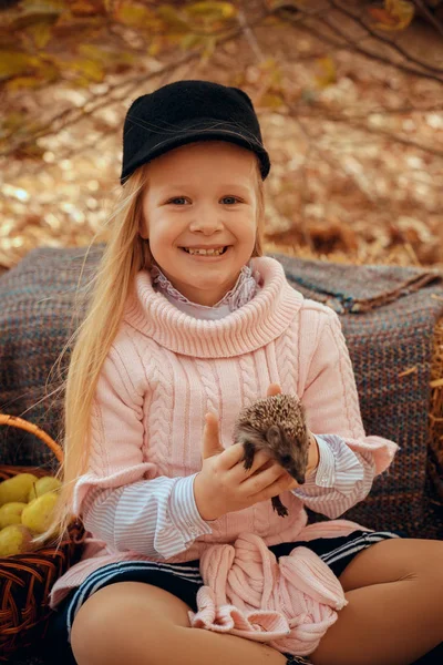 Красивая маленькая девочка с симпатичной и забавной ежиной на осенней природе — стоковое фото