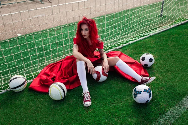 Lujosa mujer con el pelo rojo y en un vestido rojo juega en el fo —  Fotos de Stock