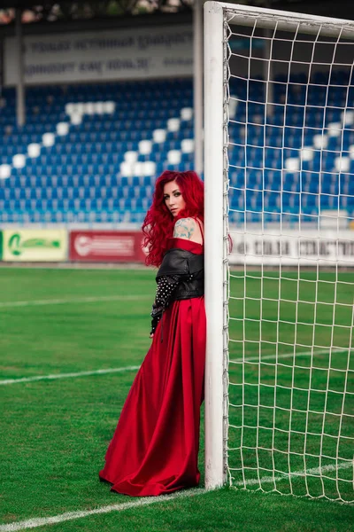 Luxusní žena s rudými vlasy a v červených šatech hraje na fo — Stock fotografie