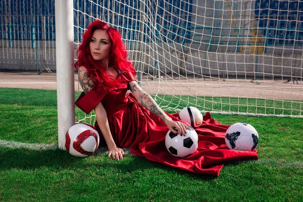 Lujosa mujer con el pelo rojo y en un vestido rojo juega en el fo — Foto de Stock