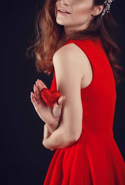 Hermoso corazoncito en las manos femeninas sobre fondo negro —  Fotos de Stock