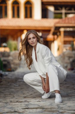 Outdoor full body fashion portrait of fashionable woman in white suit posing in street of east city