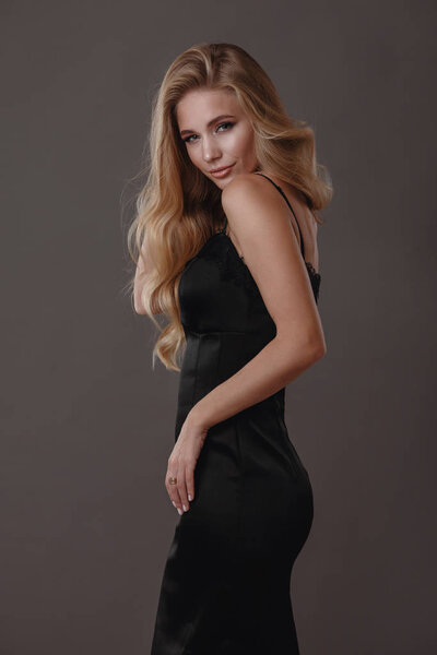 Beautiful woman in black dress in studio